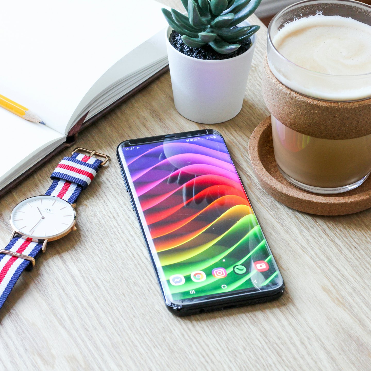 Büromaterial und ein Smartphone auf einem Holztisch.